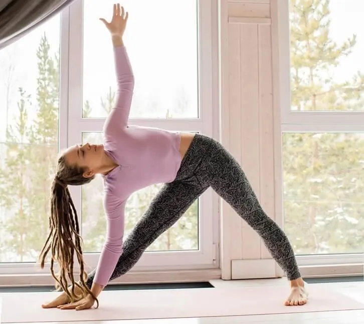 Person in triangle pose with one hand reaching toward the front shin